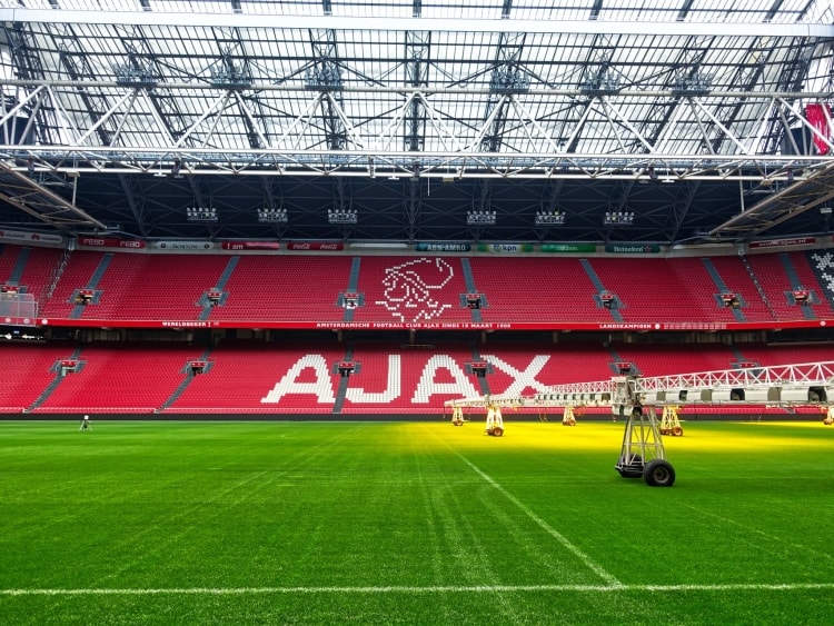 Veld en de tribune met de naam en het logo van Ajax in de Johan Cruijff ArenA
